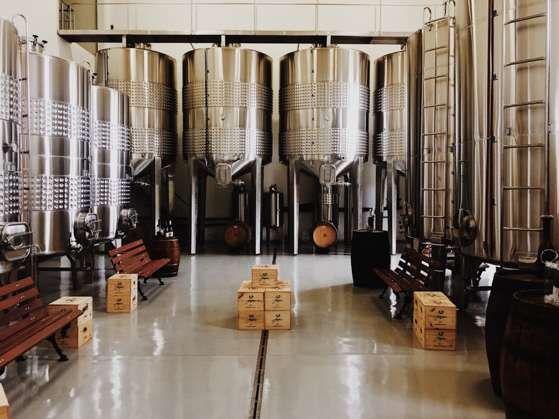 A row of tall stainless fermentation tanks in the brewery's open tank hall.