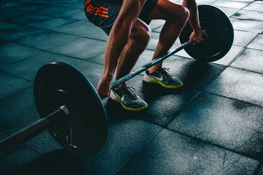 Someone deadlifting a loaded barbell on the gym floor