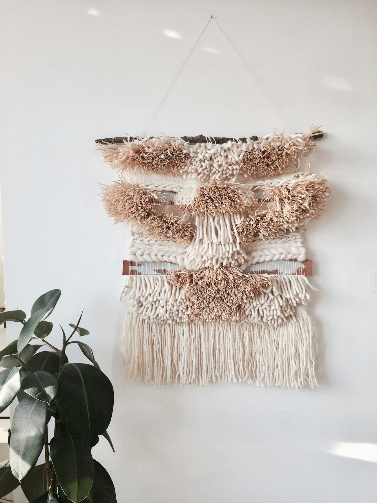 A small handmade wall hanging in oat and clay tones with hand-knotted fringe