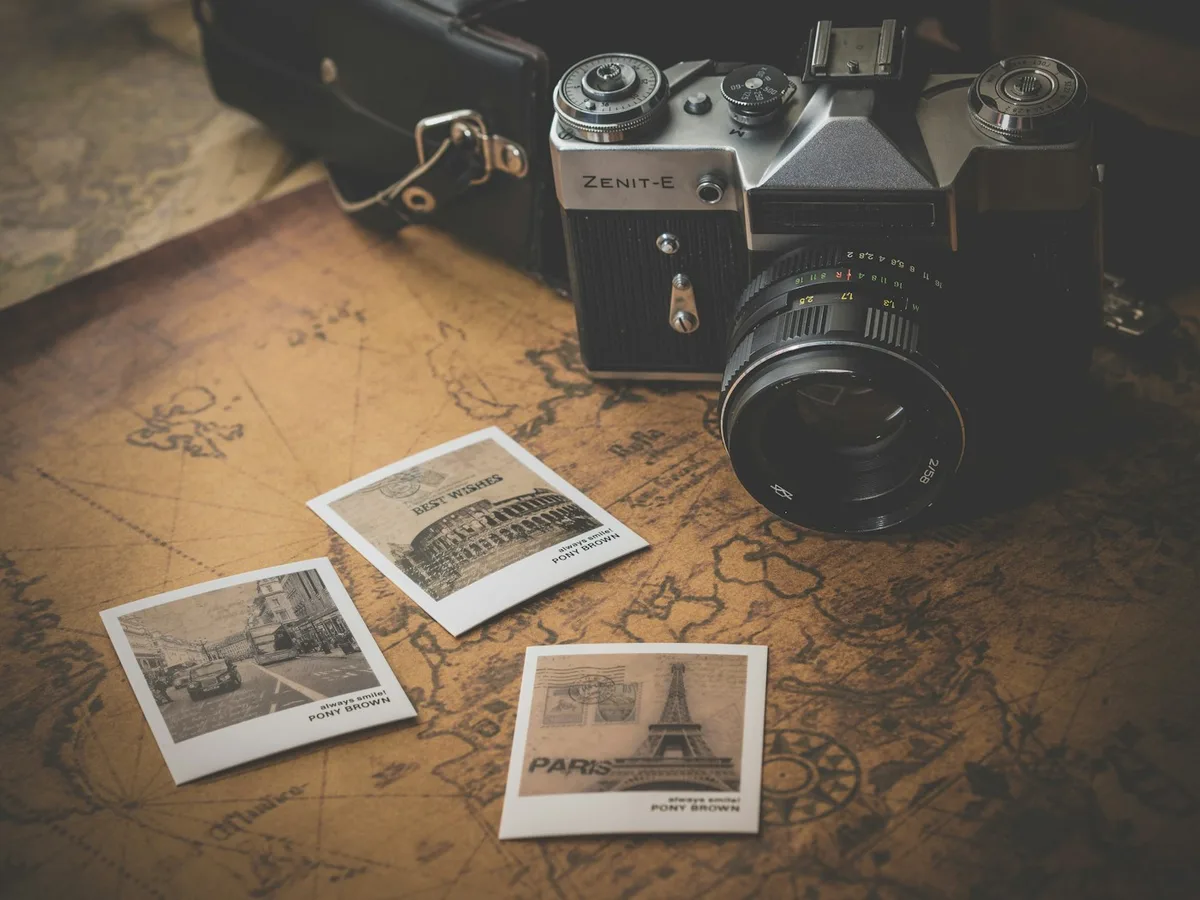 A film camera and a few printed photos resting on an old map